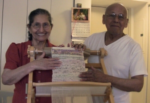 The Mejias display their completed weaving on the loom